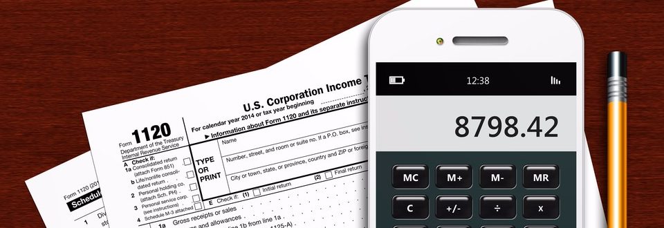 tax form 1120 with phone calculator and pencil on wooden table